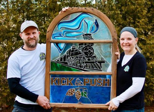 Daniel and Laina Lees with the stained glass version of the Kick and Push Brewery Logo – stained glass by Laina Lees.